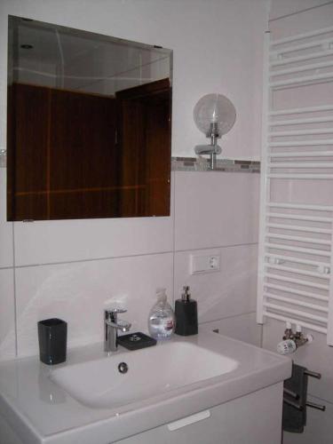 a white bathroom with a sink and a mirror at Haus Ellbogen in Momlingen