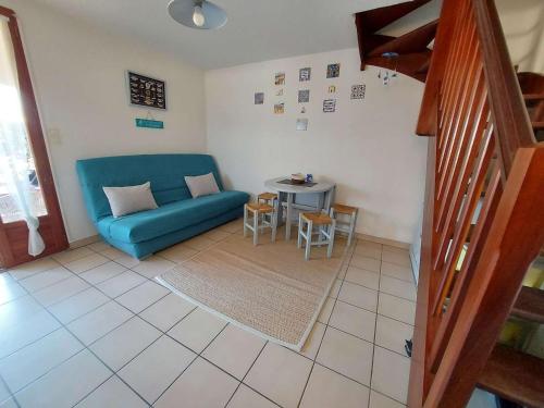 un salon avec un canapé bleu et une table dans l'établissement Charmante maison 2 pièces cabine, terrasse, BBQ, parking privé, proche plage - Marseillan - FR-1-326-562, à Marseillan