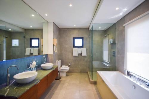 a bathroom with two sinks and a tub and a toilet at Beachfront Luxury with Incredible Ocean Views apts in Christ Church