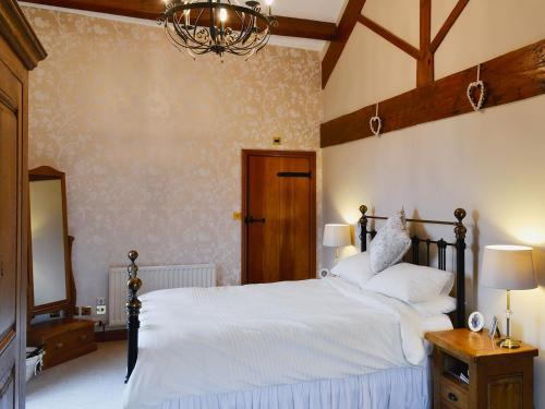 a bedroom with a bed with white sheets and a chandelier at Flatts Barn in Hebden