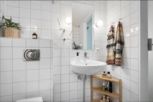 a white bathroom with a sink and a mirror at Spacious & stylish apartment in Oslo - Supercentral in Oslo