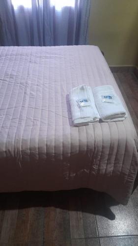 Una cama con sábanas blancas y toallas. en Cabaña la Encantada en Humahuaca