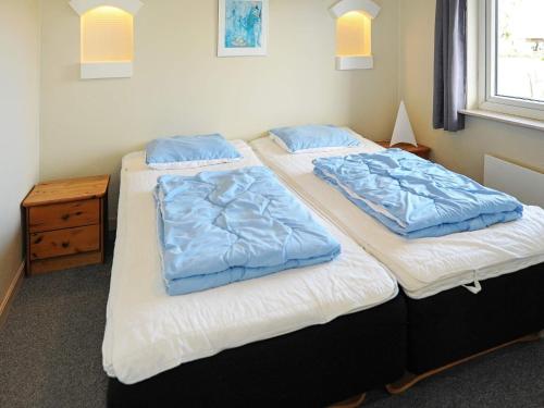twee bedden in een kamer met blauwe kussens erop bij Holiday Home Hedevang V in Oksbøl