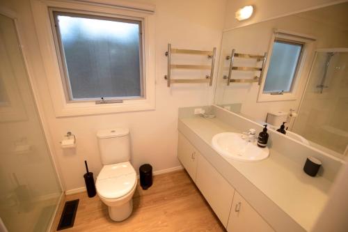 a bathroom with a toilet and a sink and a window at LONSDALE ON GLANEUSE in Point Lonsdale