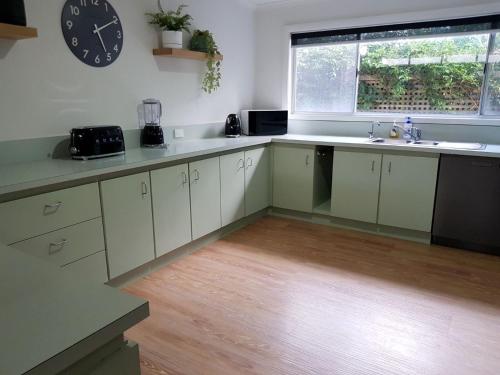 a kitchen with white cabinets and a clock on the wall at LONSDALE ON GLANEUSE in Point Lonsdale