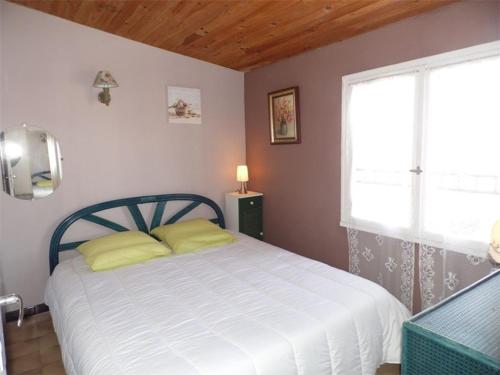 une chambre avec un lit avec des oreillers jaunes et une fenêtre dans l'établissement Duplex climatisé avec 2 chambres, grande terrasse et parking privé - FR-1-326-611, à Marseillan