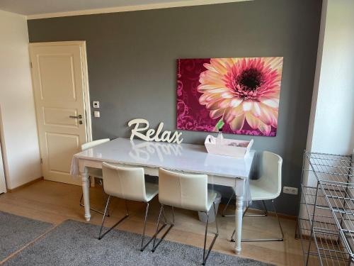 einem Esstisch mit weißen Stühlen und einem Blumengemälde in der Unterkunft Appartment im Architektenhaus - 53qm-2 Schlafzimmer-Küche-Bad -2min von A8 - ruhig in Irschenberg
