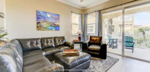 a living room with a leather couch and chair at SouthernVilla Ticket to Paradise in Palm Coast