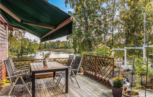 a wooden deck with a table and chairs and a lake at Lovely Home In Munka-Ljungby With Wifi in Munka-Ljungby