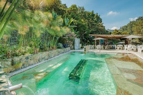 uma piscina de beiral infinito com cadeiras e mesas num quintal em Hotel Termales Tierra Viva em Manizales