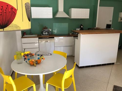 une cuisine avec une table blanche et des chaises jaunes dans l'établissement Appartement T2 climatisé avec balcon, WiFi et parking près du centre de Cavalaire-sur-Mer - FR-1-100-180, à Cavalaire-sur-Mer
