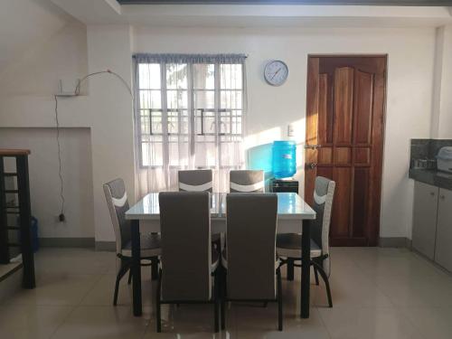 a dining room with a table and chairs and a clock on the wall at Mando Manor -3 Bedroom Private House for Large Group in Tacloban