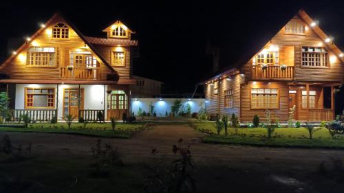 a large wooden house at night with lights at La Cabaña de Mari in Oxapampa