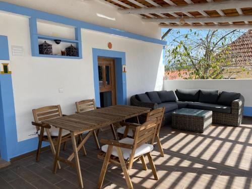 a patio with a wooden table and chairs and a couch at Casa do Papillon in Mata de Cima