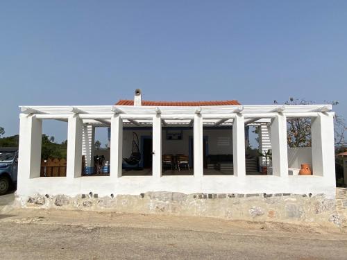 a white house with white columns on a street at Casa do Papillon in Mata de Cima