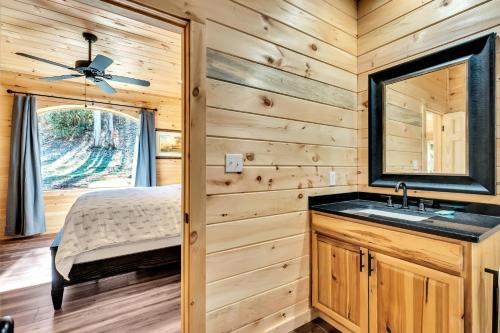 Blockhausschlafzimmer mit einem Waschbecken und einem Spiegel in der Unterkunft Bo's Carriage House - private 36-acre resort with 6 homes amazing waterfall in Cosby
