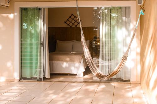 a hammock in a bedroom with a bed at Pousada Aldeia's in Aragarças