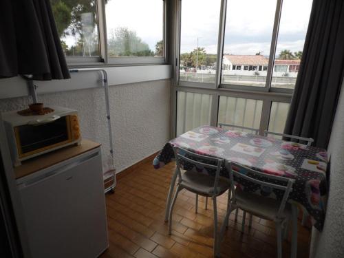 Il comprend une petite cuisine avec une table, des chaises et un four micro-ondes. dans l'établissement Appartement cosy à 200m de la plage avec parking privé et loggia, animaux admis - FR-1-326-668, à Marseillan