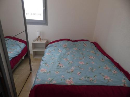 une chambre avec un lit avec une couette bleue dans l'établissement Appartement cosy à 200m de la plage avec parking privé et loggia, animaux admis - FR-1-326-668, à Marseillan