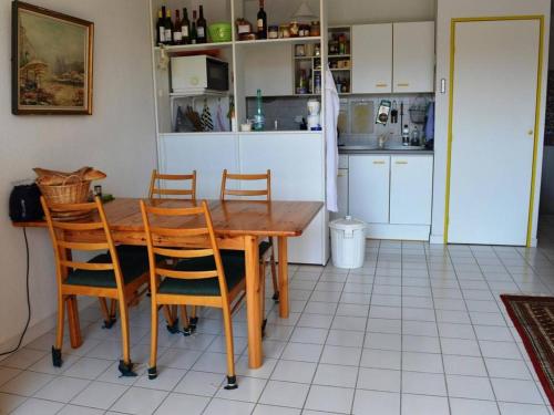 une cuisine avec une table en bois et quatre chaises dans l'établissement Duplex 4 pièces avec terrasse et solarium, 150m de la mer, parking privé, ascenseur - FR-1-225-655, à Argelès-sur-Mer