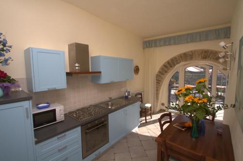 a kitchen with white cabinets and a table with a vase of flowers at Appartamenti Chiarina in Dolcedo
