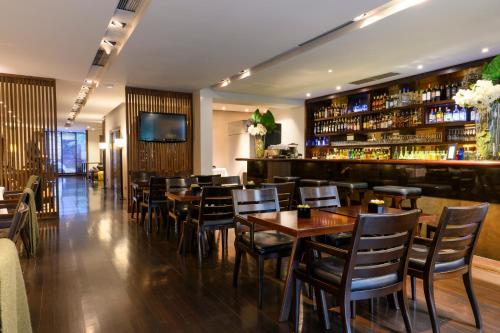Un restaurante con mesas y sillas de madera y un bar. en Libertad Hotel Buenos Aires, en Buenos Aires