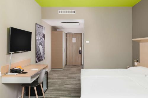 a hotel room with a bed and a desk and a television at Park Inn By Radisson Budapest in Budapest