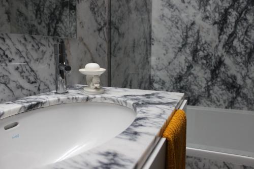 a bathroom with a white sink and a tub at Groove-Wood Loft in Vila Nova de Gaia