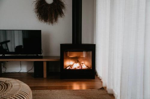 a fireplace in a living room with a table and a television at Bangalay Luxury Villas in Shoalhaven Heads