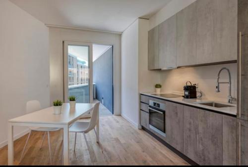 una cucina con tavolo bianco, tavolo bianco e tavolo e una cucina di 5 Rent Apartments Lugano Station a Lugano