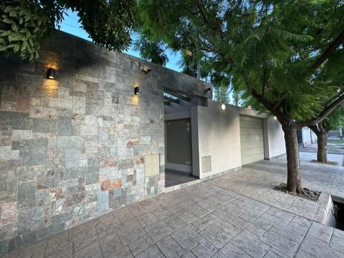 un edificio de piedra con un árbol delante de él en Orfila Apart 5 en Mendoza