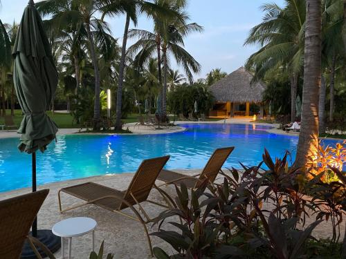 a pool with chairs and a umbrella and a table at Departamento totalmente nuevo en la Isla Residence Acapulco in Acapulco