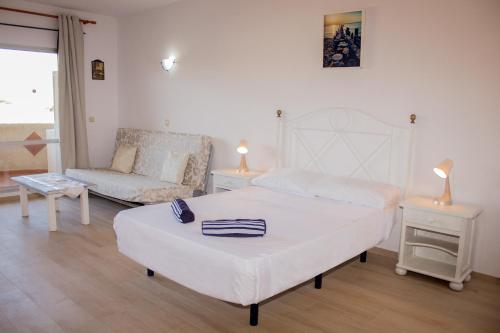 una camera bianca con un letto e un divano di Benal beach suite II, estudio con parque acuático y vistas al mar. a Benalmádena