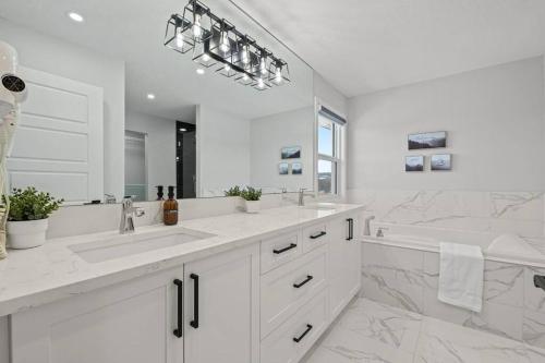 a white bathroom with two sinks and a tub at Luxury-4bed with AC-86"TV-BrandNew in Cranston, Calgary in Calgary