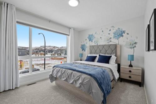 a bedroom with a bed and a large window at Luxury-4bed with AC-86"TV-BrandNew in Cranston, Calgary in Calgary