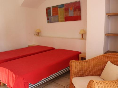 - une chambre avec deux lits rouges et une chaise dans l'établissement Villa de charme en pinède, 4 chambres climatisées, accès direct plage - FR-1-100-209, à Cavalaire-sur-Mer