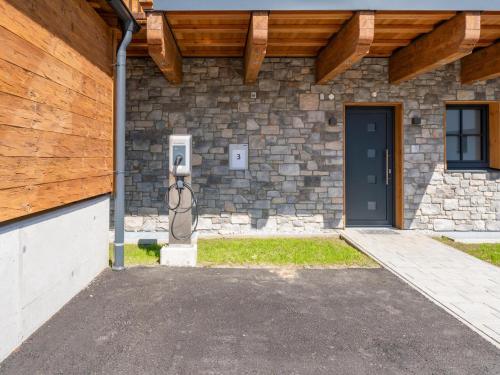 a stone building with a door and a wooden roof at Pinzgau Lodge 2D in Wald im Pinzgau