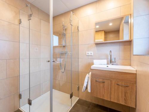 uma casa de banho com um chuveiro, um lavatório e um espelho. em Haus Wald em Wald im Pinzgau