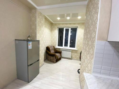 uma cozinha com um frigorífico e uma cadeira num quarto em apartment near Cosmopark complex em Bishkek