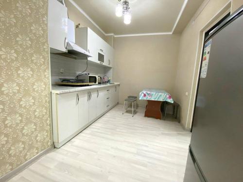 uma cozinha com armários brancos e uma mesa em apartment near Cosmopark complex em Bishkek