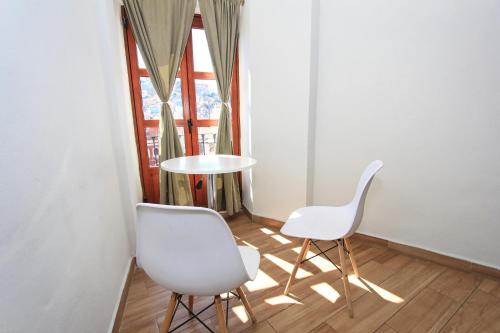 Duas cadeiras brancas e uma mesa num quarto com uma janela em Hotel Grand Guanajuato em Guanajuato