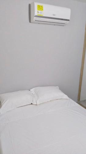 1 cama blanca con sábanas blancas y una luz en la pared en Apartamento Amoblado en Barranquilla, en Barranquilla