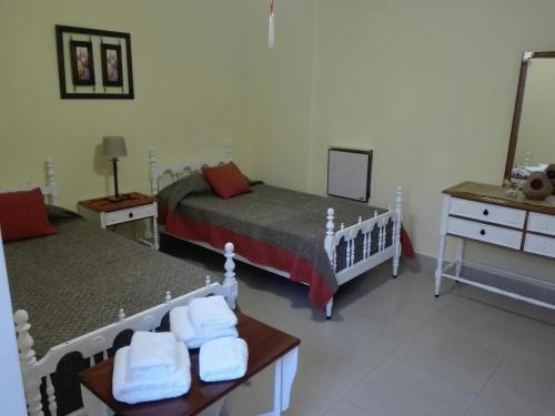 a bedroom with two beds and a table with towels at Hostal Virgen del Rosario Cafayate in Cafayate