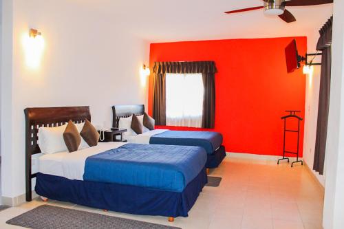 sypialnia z 2 łóżkami i czerwoną ścianą w obiekcie Real de la Presa w mieście Guanajuato