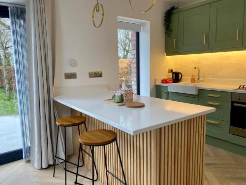 una cocina con armarios verdes y una barra con taburetes en Modern Space 20 minutes from Dublin Airport, en Dunboyne