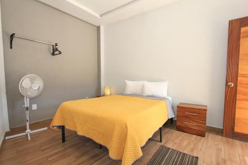 a bedroom with a bed with a yellow blanket and a fan at Hotel Grand Guanajuato in Guanajuato