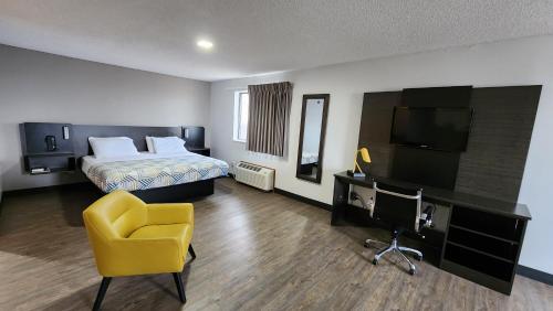 Habitación de hotel con cama y silla amarilla en Motel 6-Kewanee, IL, en Kewanee