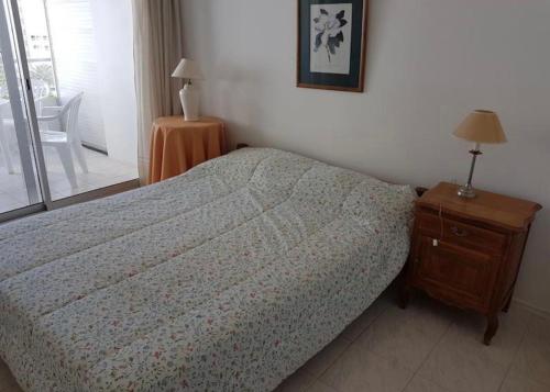 1 dormitorio con 1 cama y 1 mesa con lámpara en Complejo Linchol Center, Torre Madison, en Punta del Este