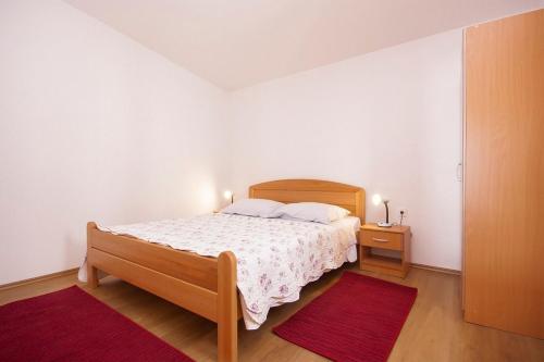een witte slaapkamer met een bed en een nachtkastje bij Apartments with a parking space Grebastica, Sibenik - 13978 in Bašelovići