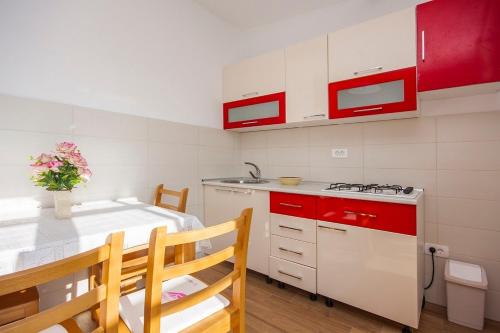 eine Küche mit roten und weißen Schränken und einem Tisch in der Unterkunft Apartments with a parking space Grebastica, Sibenik - 13978 in Bašelovići